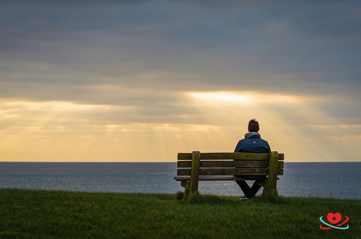 Мужчина сидит в одиночестве на лавке